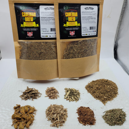 Two pouches of Caveman Brew Roots Tea standing behind a display of its eight raw, wildcrafted herbal ingredients including Channey Root and Medina, neatly arranged on a white surface
