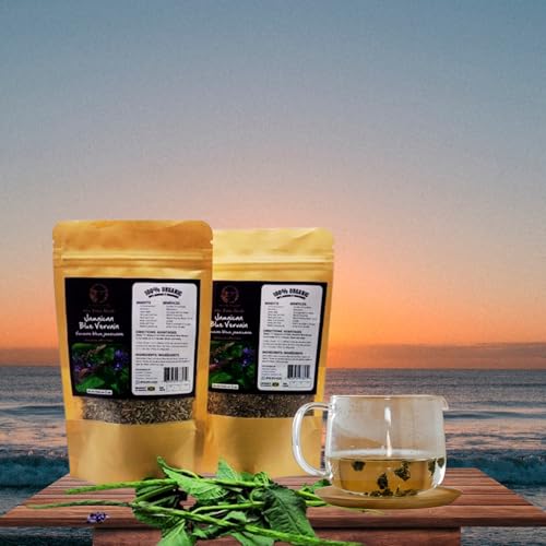 Two pouches of Inspired Gems Organic Jamaican Blue Vervain Tea next to a glass mug of brewed herbal tea on a wooden table, with a sunset and ocean waves in the background